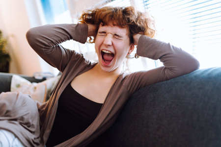 Portrait young woman yawning while sitting on sofaの写真素材
