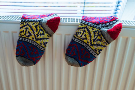 Woolen socks dry on radiator on cold winter day.