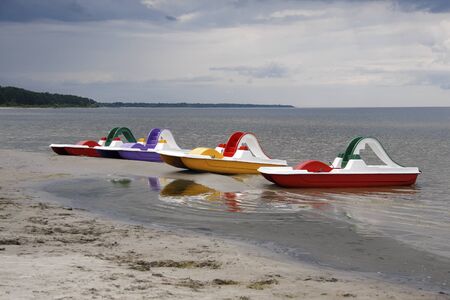 Four bright multi-colored catamarans moored to the shore. Riga seaside (Baltic Sea) before a thunderstorm.の写真素材