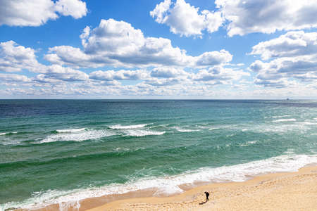 Beautiful seascape: endless sea, turquoise water, blue sky, white clouds, golden sand. Silhouette of...
