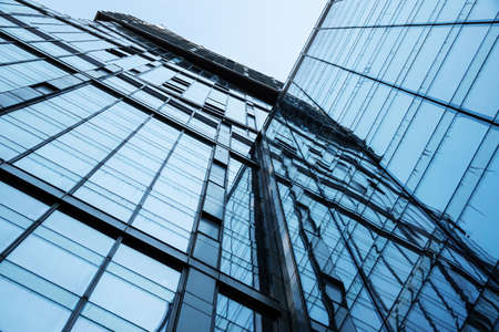 Abstract bottom view of a modern glass building with reflections and sky. Urban geometry, modern architecture, abstract architectural design.の写真素材