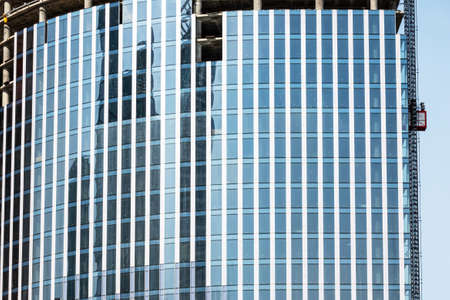 Moscow, Russia - April 13, 2021: Close-up fragment of a modern skyscraper under construction with reflections in the mirror surface.のeditorial素材