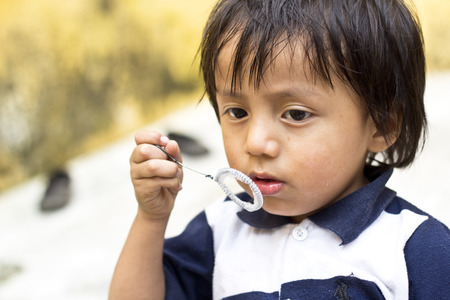ANTIGUA, GUATEMALA - SEPTEMBER 15, 2013:  Boy tries to blow soap bubbles while playing around the earthquake ruins of Antigua. September 15, 2013, in Antigua, Guatemalaのeditorial素材