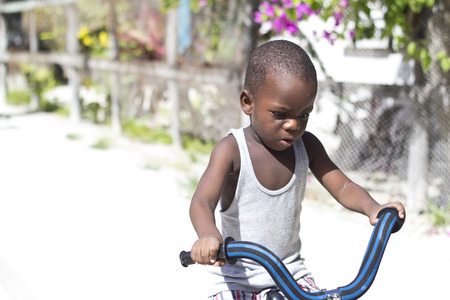 CAYE CAULKER, BELIZE - SEPTEMBER 20, 2013: Boy tries to learn how to ride a bike September 20, 2013 in Caye Caulker, Belize. Belize is considered the 4th happiest country in the worldのeditorial素材