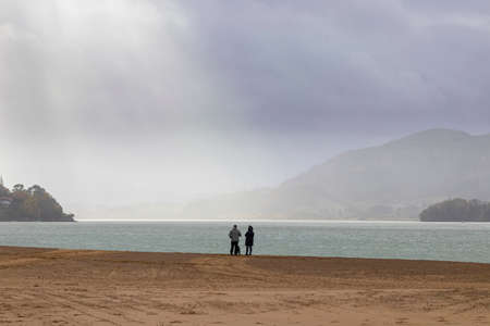 people in a beach in winter in the basque country looking to the horizon