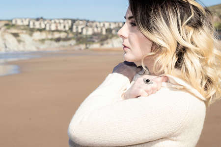 blonde woman looking at the horizon pensive wearing a woolen sweater