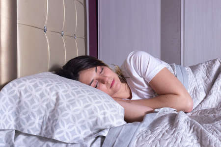 woman sleeping in bed in a white t-shirtの写真素材