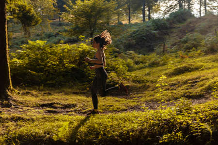 woman running with sportswear through a beech forest in the mountains of vizcaya
