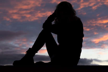 silhouette of sensual woman sitting at sunsetの写真素材