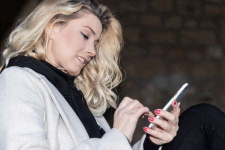 attractive blonde woman typing on mobile
