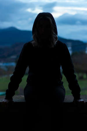 silhouette of sitting woman looking at camera with aggressive attitudeの写真素材