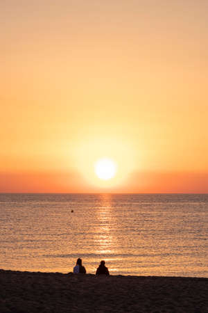 young couple watching the sunrise on the beachの写真素材