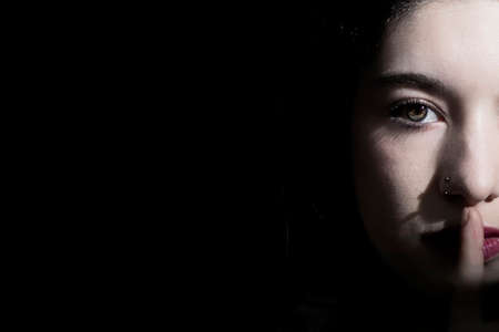 half face of woman ordering silence with black background