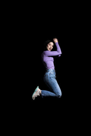 brunette woman jumping on black background