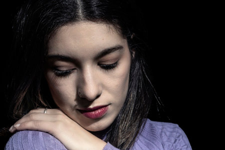 brunette woman looking at her shoulder with black backgroundの写真素材