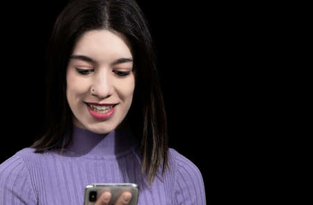 smiling brunette woman looking at the mobile with black background