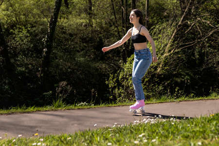 brunette woman skating in the park with pink roller skatesの写真素材