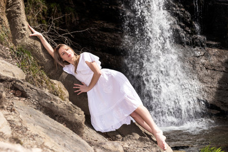 woman lying in a waterfall in a white dressの写真素材