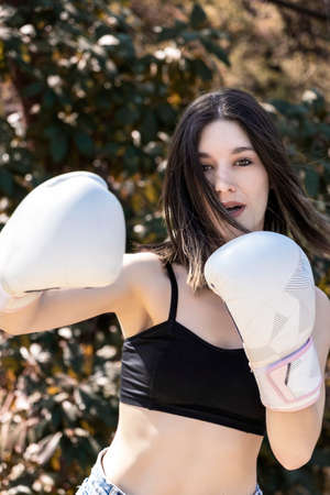 young female boxer with white gloves in a parkの写真素材