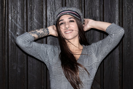 Stylish girl posing near the wooden wall. Photo of woman with capの写真素材