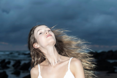 pretty woman moving her hair on the beach at sunsetの写真素材