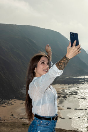 excited woman taking a selfie while standing on the seacoastの写真素材