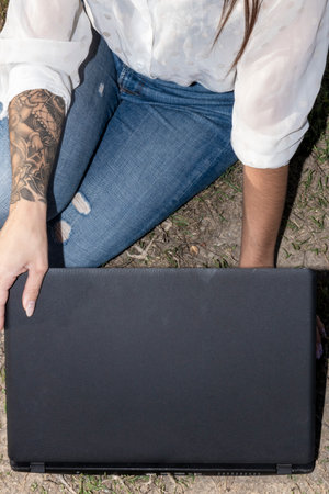 Digital nomad lifestyle concept with adult woman sit down on the ground with scenic view of beach...