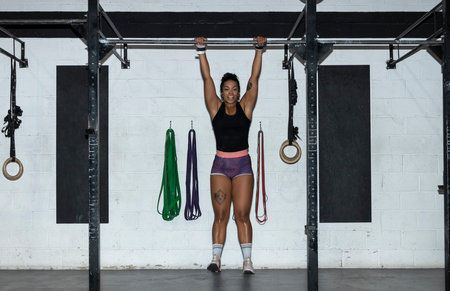 Fitness toes to bar woman pull ups 2 bars workout exercise at gym.Woman working out on cross bars in...