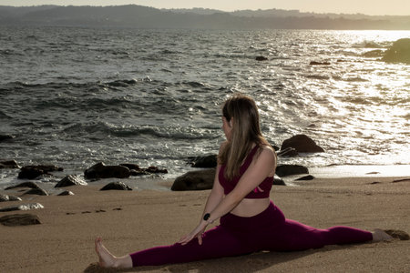 young pretty flexible blonde woman doing stretching on the beach