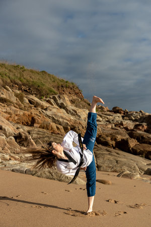 woman doing taekwondo on the beach giving a kick to the airの写真素材