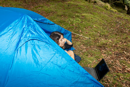 digital nomad woman in the bush with a tent working with a laptopの写真素材