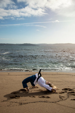 woman doing bridge handstand on the beach wearing taekwondo clothesの写真素材