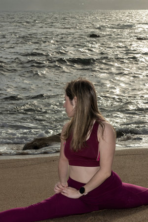 young pretty flexible blonde woman doing stretching on the beachの写真素材