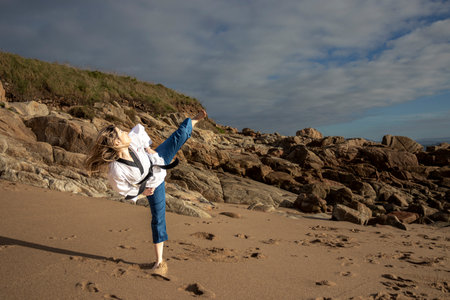 woman doing taekwondo on the beach giving a kick to the airの写真素材