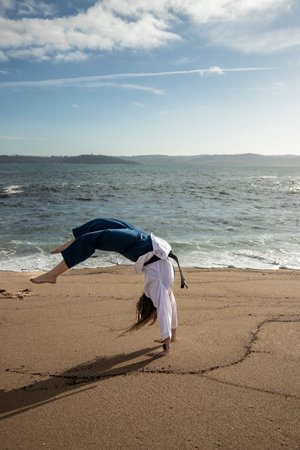 woman cartwheeling in kimono on the beachの写真素材