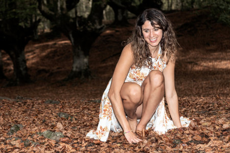 Autumn Beauty: A Joyful Woman in a Long Dress Amongst Vibrant Foliageの写真素材