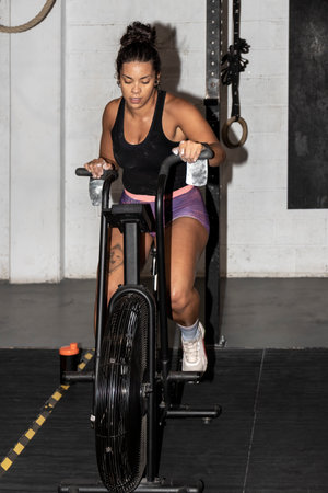 Pedaling to Fitness: A Latina Womans Determination Shines in the Gyms Indoor Cycling Sessionの写真素材