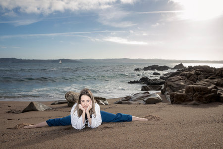Seaside Spagat: Talented Young Woman Showcasing her Stretching Prowess in Taekwondo Gearの写真素材