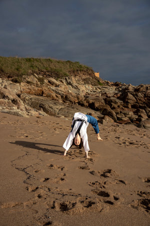 Dynamic Beach Workout: Taekwondo-Clad Woman Displaying Acrobatics and Strength by the Shoreの写真素材