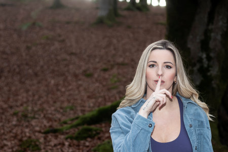 Whispering Serenity: Blonde Woman Embraces the Tranquility of an Autumn Forestの写真素材