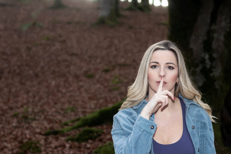 Whispering Serenity: Blonde Woman Embraces the Tranquility of an Autumn Forestの写真素材