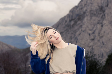 Captivating Alpine Serenity: Smiling Woman's Hair Dance in the Wind Amidst Mountain Blissの写真素材
