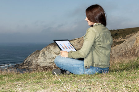 Remote Work: Productive Laptop Session by a Nature-Embracing Working Womanの写真素材