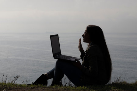 Tranquil Evening as a Brunette Woman Engages in Laptop Video Callの写真素材