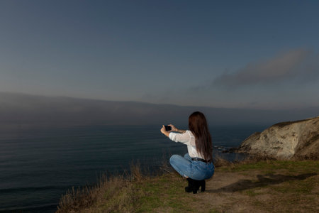Young Woman Captures Coastal Beauty Through Her Mobile Lensの写真素材