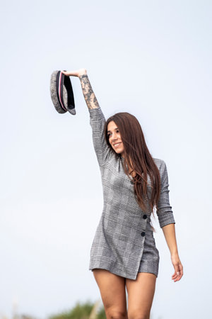 Youthful Urban Elegance: Confident Brunette in a Short Dress and Hat, Flaunting Expressive Tattoosの写真素材