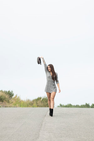 Trendy Woman Balances Short Dress, Cap, and Tattooed Arm for Contemporary Appealの写真素材