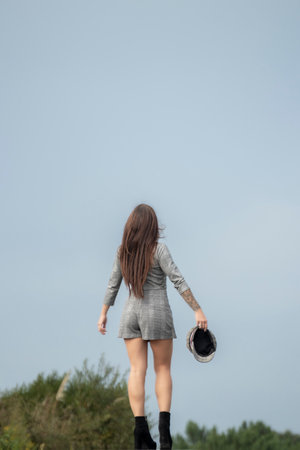Stylish Woman Carrying Cap Embarks on a Journey, Wearing Checkered Dressの写真素材