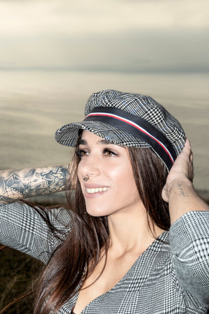 Confident Young Woman in Gray Plaid Dress and Capの写真素材