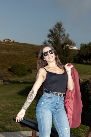 Urban Elegance: Stylish Brunette, Adorned with Tattoos and Piercings, Radiates Confidence in Red Jacketの写真素材